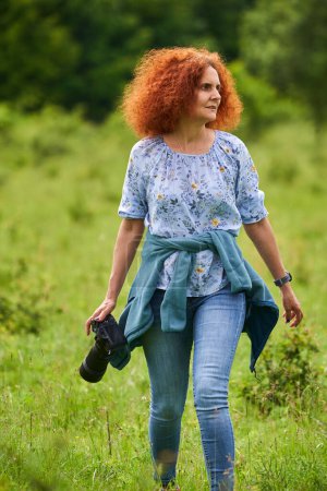 Photo for Woman nature photographer with camera on a meadow in the wilderness - Royalty Free Image
