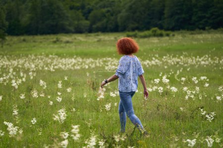 Téléchargez les photos : Portrait d'une femme rousse aux cheveux bouclés sur une prairie dans une forêt de chênes - en image libre de droit