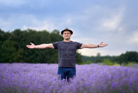 Foto de Agricultor con sombrero en medio de su campo de lavanda, listo para la cosecha - Imagen libre de derechos