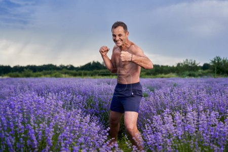 Téléchargez les photos : Kickboxer entraînement de combat dans un champ de lavande en pleine floraison - en image libre de droit