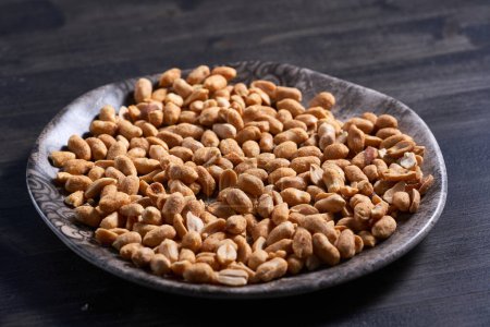 Photo for Closeup of crusty peanuts on a plate on a wooden board - Royalty Free Image
