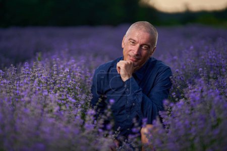 Photo for Mature man in a lavender field at sunset, professional light setup - Royalty Free Image