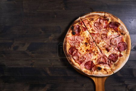 Foto de Tiro plano de una pizza recién horneada en una tabla de madera - Imagen libre de derechos