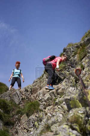 Photo for Two women hikers with backpacks hiking on a trail in the rocky mountains - Royalty Free Image