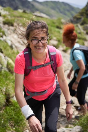 Téléchargez les photos : Deux randonneuses avec sacs à dos randonnée sur un sentier dans les montagnes rocheuses - en image libre de droit