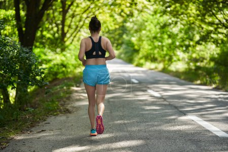 Photo for Woman runner jogging on asphalt road in forest - Royalty Free Image