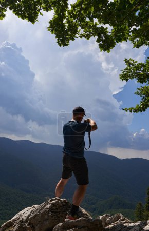 Téléchargez les photos : Photographe nature homme photographiant des paysages au sommet d'une montagne - en image libre de droit