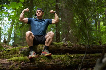Photo for Man sitting on a tree log covered in moss after a hike - Royalty Free Image