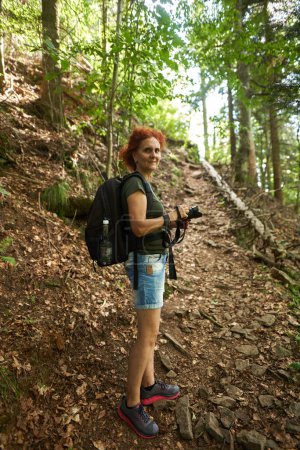 Photo for Woman hiker with backpack and camera hiking into the mountain forest - Royalty Free Image
