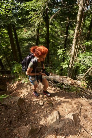 Foto de Mujer excursionista con mochila y cámara de senderismo en el bosque de montaña - Imagen libre de derechos