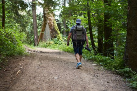 Foto de Fotógrafo de naturaleza profesional con mochila caminando por el bosque en las montañas con cámara - Imagen libre de derechos
