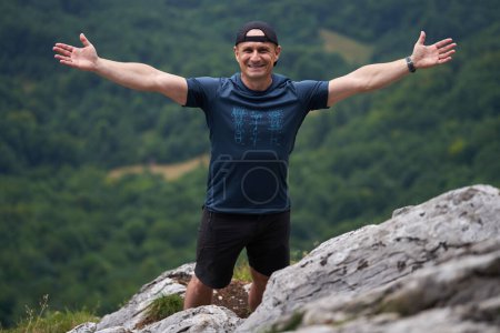 Photo for Strong athletic man on top of the mountains with forest in distant background - Royalty Free Image