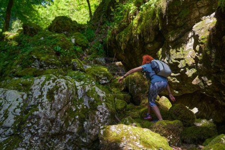 Téléchargez les photos : Femme randonneuse avec sac à dos explorant une belle gorge avec une rivière dedans - en image libre de droit