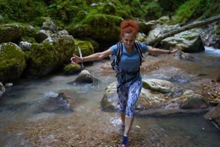 Photo for Woman hiker with backpack exploring a lush canyon with a river in it - Royalty Free Image
