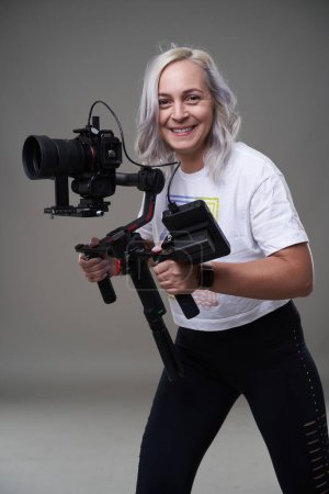 Photo for Woman videographer with cinema camera on gimbal on gray background - Royalty Free Image