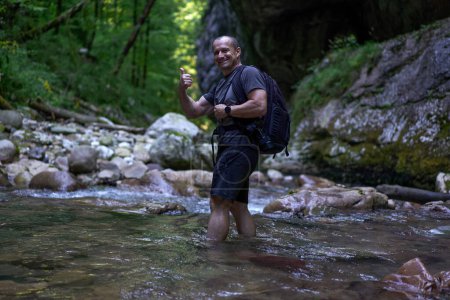 Téléchargez les photos : Photographe de nature professionnel avec sac à dos prenant des photos dans une gorge - en image libre de droit