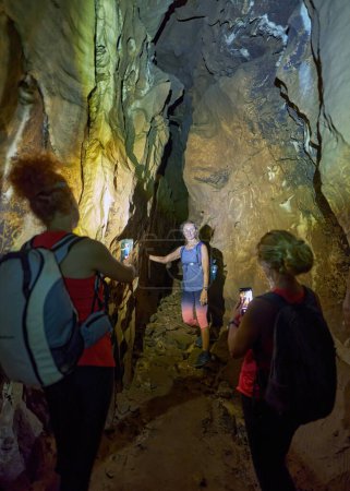Photo for Three women with backpack exploring a cave with head torches - Royalty Free Image