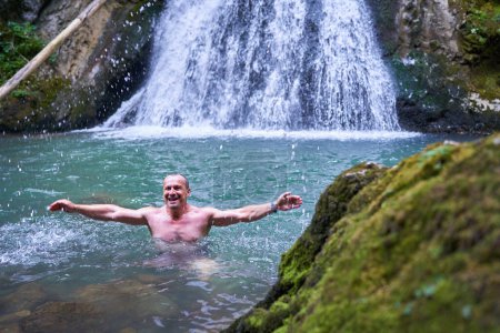 Foto de Hombre atlético fuerte bañándose en una cascada con agua helada de montaña - Imagen libre de derechos