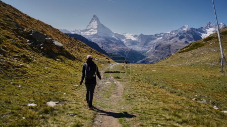 Photo for Young woman hiker on a hiking trail towards the Matterhorn peak in Swiss Alps - Royalty Free Image