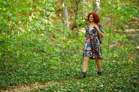 Téléchargez les photos : Portrait d'une belle rousse bouclée en robe florale dans le parc - en image libre de droit