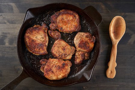 Foto de Sartén de hierro fundido cocido solomillo de cerdo frito en una tabla de madera - Imagen libre de derechos