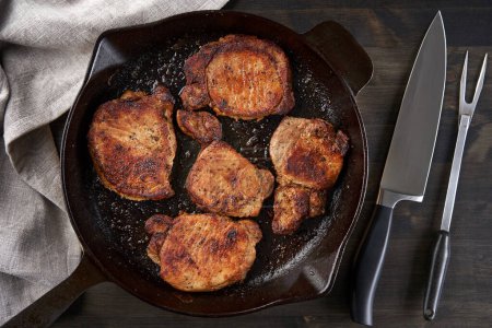 Photo for Cast iron skillet cooked fried pork tenderloin on a wooden board - Royalty Free Image