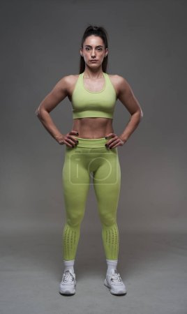 Téléchargez les photos : Modèle hispanique attrayant de remise en forme posant en tenue de gym sur fond gris - en image libre de droit