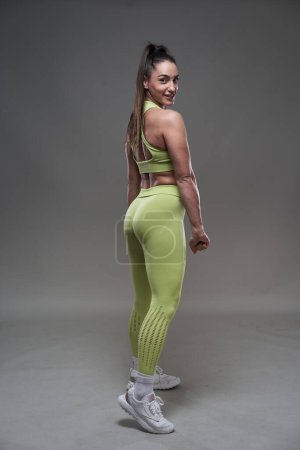 Téléchargez les photos : Modèle hispanique attrayant de remise en forme posant en tenue de gym sur fond gris - en image libre de droit