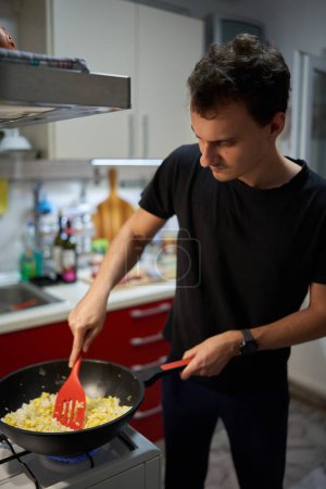 Foto de Joven preparando un arroz frito con huevos receta asiática en un wok en una estufa de gas - Imagen libre de derechos