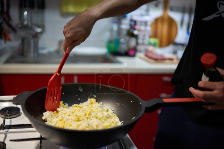 Photo for Hands of a young man making fried rice with eggs in a work, asian recipe, on a gas stove - Royalty Free Image