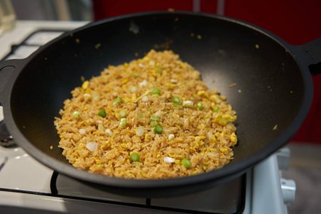 Foto de Arroz frito con huevos, una receta asiática, preparándose en un wok sobre una estufa de gas - Imagen libre de derechos