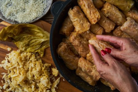 Photo for Woman's hands preparing cabbage rolls with pork meat and rice, sarmale, a traditional Romanian dish - Royalty Free Image