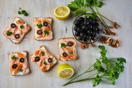 Photo for Smoked salmon with herbs and olives on bruschetta bread, mediterranean appetizer, on a wooden board - Royalty Free Image