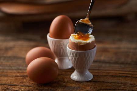 Photo for Soft boiled egg in cup on a wooden board, runny yolk visible - Royalty Free Image