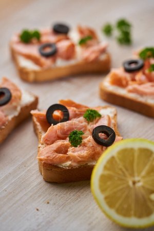 Photo for Closeup of smoked salmon fillet bites on crostini breads with herbs and olives, appetizer - Royalty Free Image