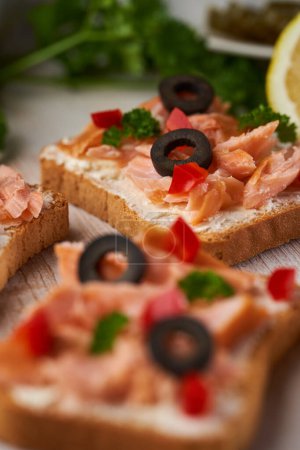 Téléchargez les photos : Gros plan de bouchées de filet de saumon fumé sur des pains crostini aux herbes et aux olives, apéritif - en image libre de droit