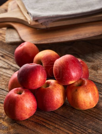 Foto de Manzanas rojas en una tabla de madera rústica, por algunas tablas de cortar y toallas - Imagen libre de derechos