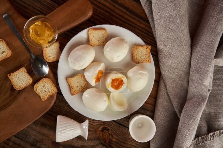 Photo for Soft boiled eggs on a plate on a wooden board, with bruschetta crackers and mustard, flat lay studio shot - Royalty Free Image