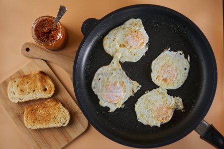 Photo for Breakfast with fried eggs in a pan and mashed vegetables chutney on toast - Royalty Free Image