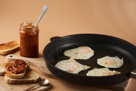 Photo for Breakfast with fried eggs in a pan and mashed vegetables chutney on toast - Royalty Free Image