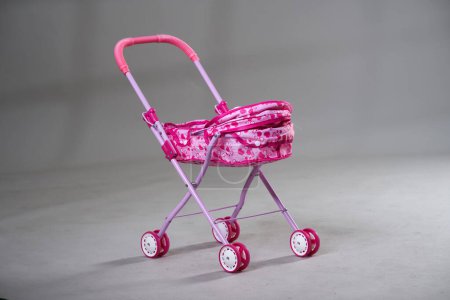 Téléchargez les photos : Jouet chariot bébé rose sur fond gris - en image libre de droit
