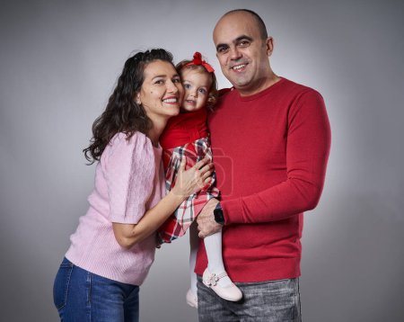 Foto de Feliz familia joven con una niña y sus padres, estudio filmado sobre fondo gris - Imagen libre de derechos