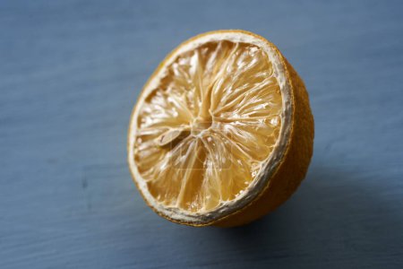 Téléchargez les photos : Demi citron tranché séché sur une planche de bois bleu, gros plan - en image libre de droit