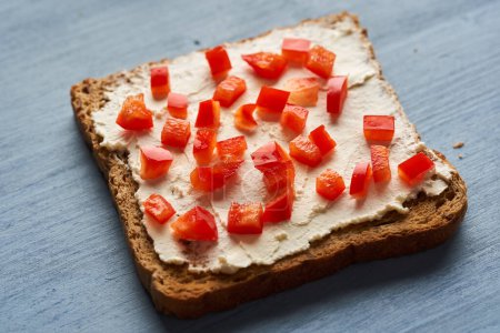Foto de Pimienta roja sobre crema de queso untada sobre pan tostado de centeno, primer plano - Imagen libre de derechos