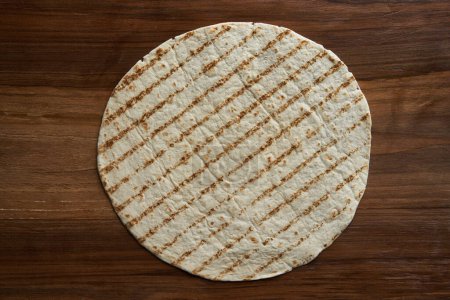 Photo for Flat lay shot of tortilla wrap on a wooden walnut board - Royalty Free Image