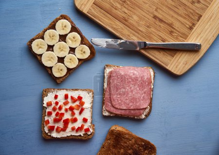 Foto de Varios sándwiches con salami, chocolate y plátano, queso crema y pimiento rojo para el desayuno o el almuerzo - Imagen libre de derechos