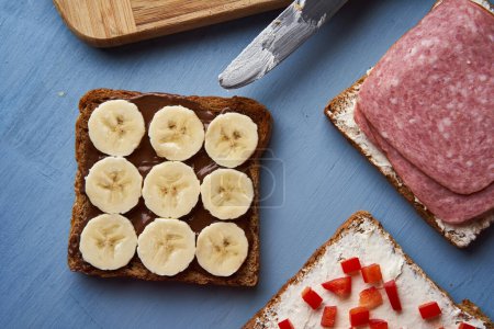 Foto de Varios sándwiches con salami, chocolate y plátano, queso crema y pimiento rojo para el desayuno o el almuerzo - Imagen libre de derechos