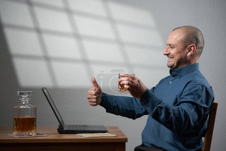 Foto de Empresario celebrando en una videoconferencia con un vaso de whisky, después de llegar a un acuerdo - Imagen libre de derechos