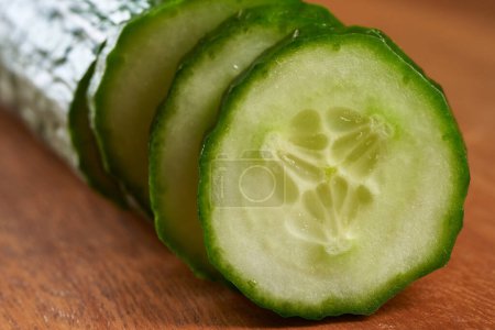 Photo for Juicy fresh cucumber sliced on a wooden board - Royalty Free Image