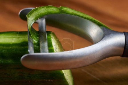 Photo for Peeling a cucumber, in closeup detail on the peeler knife - Royalty Free Image